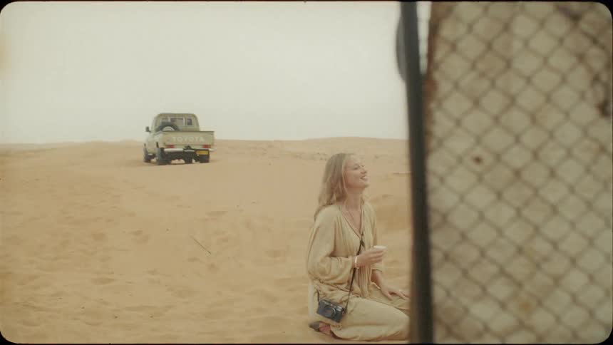Woman and two men talk as they kneel on the sand