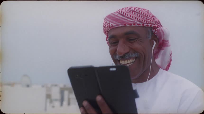 A man laughs while using a phone on the rooftop