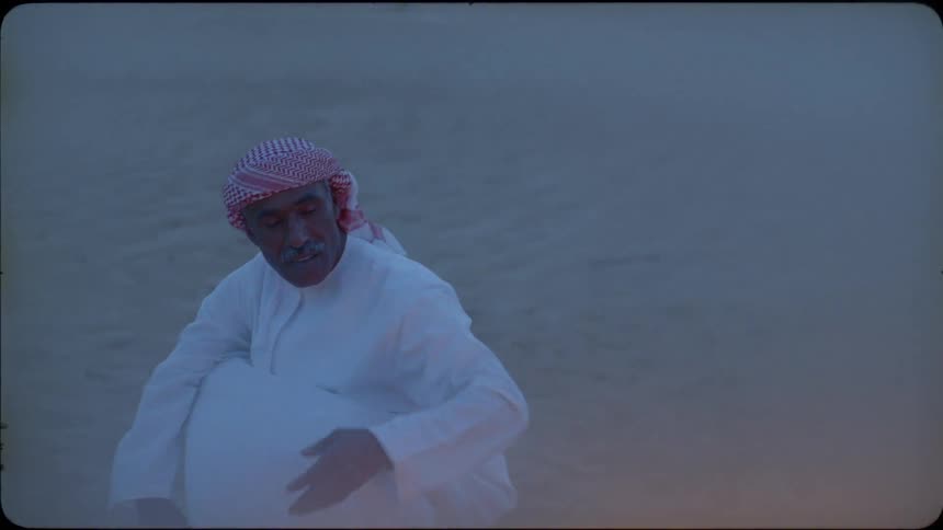 Man throws kindling on a fire outside in the desert