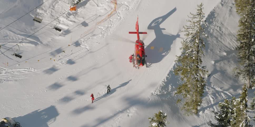 People walking on a snowy landscape away from a red helicopter