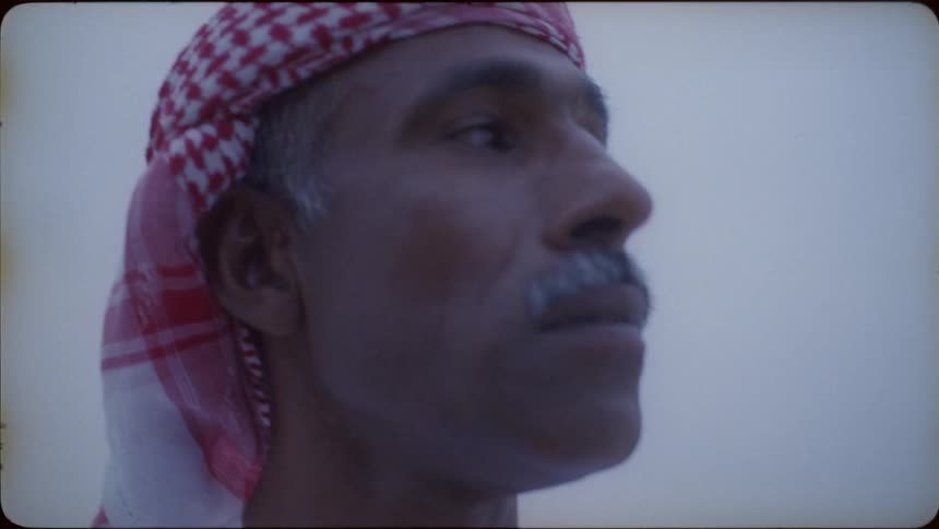 A man wearing a turban is standing under the cloudy sky