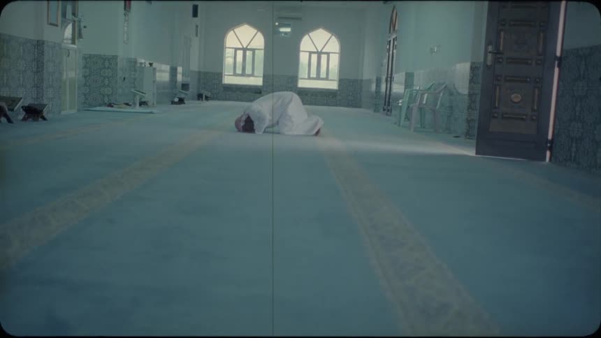 A middle eastern man prays in a mosque