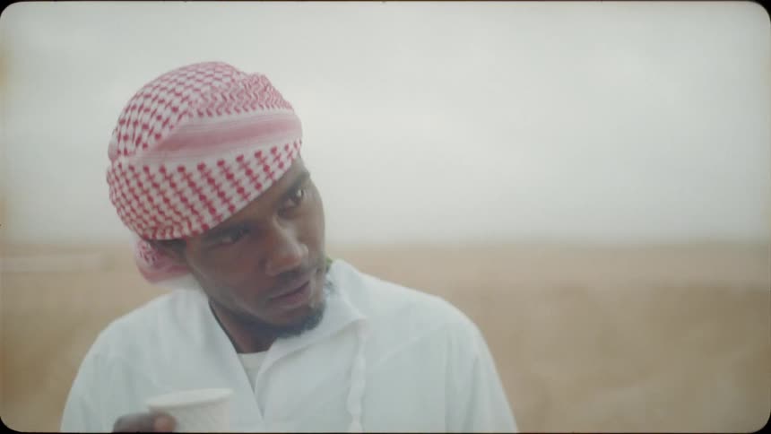 An arab man is nodding his head as he talks outside in daylight
