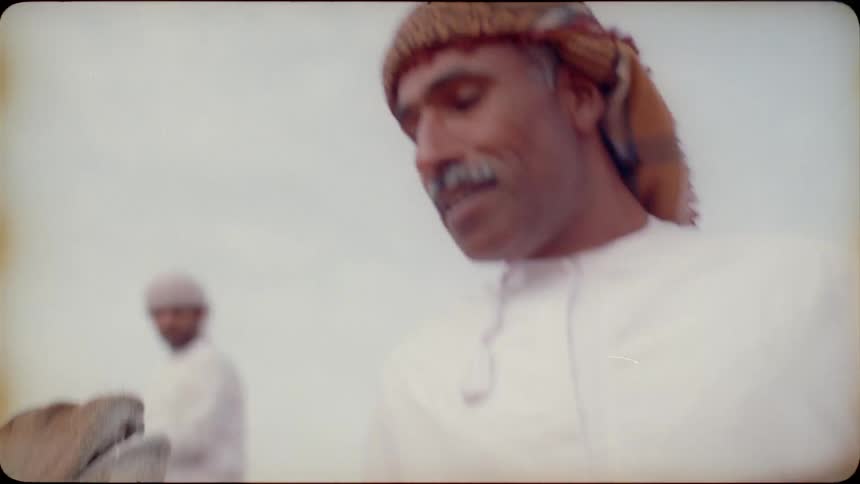 Middle eastern men lead camels in the desert