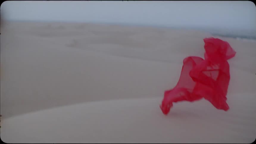 A scarf floats and falls with the breeze in a desert landscape in daylight