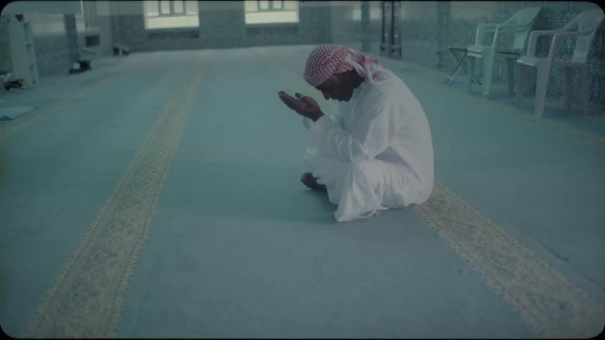 A middle eastern man sits on the ground and prays