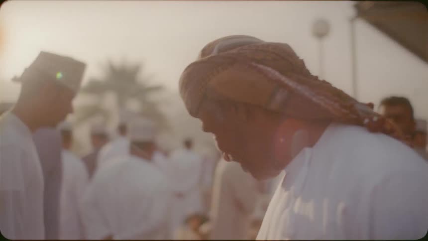 Man smiles in a crowd and looks down on a sunny day