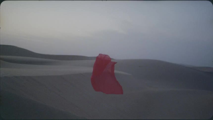 A scarf floats and falls with the breeze at dusk in a desert landscape