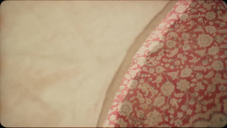 White curtain blows in the breeze over a red and white rug