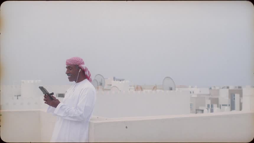 A man stands on a roof top and talks on his phone
