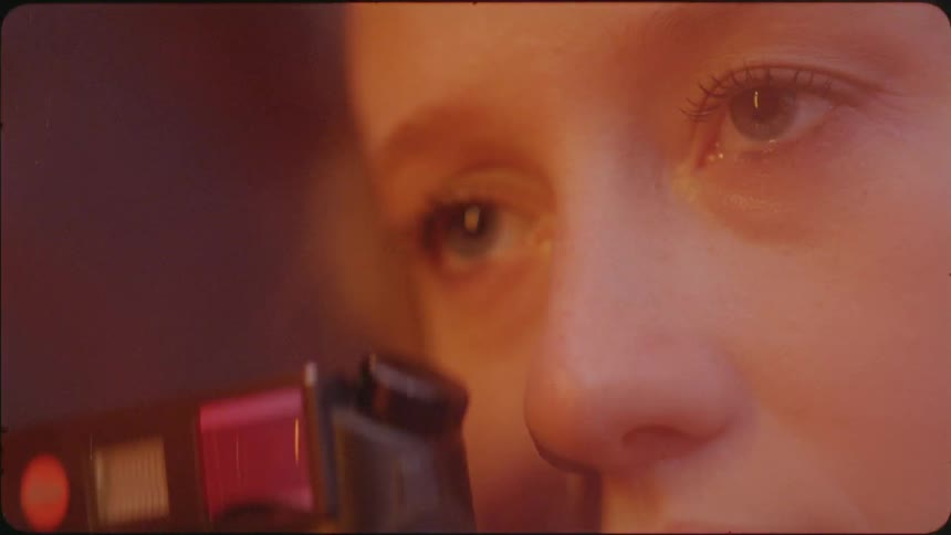A woman takes a photograph as lights shine on her face
