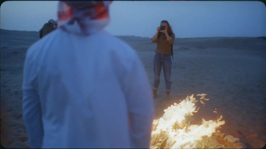A woman takes a photograph in the desert