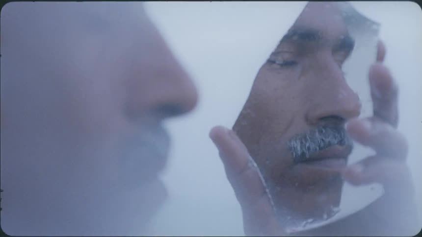 A man is holding a broken mirror in his hand