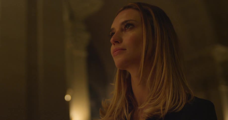 A blonde woman looking upwards and then down in a church