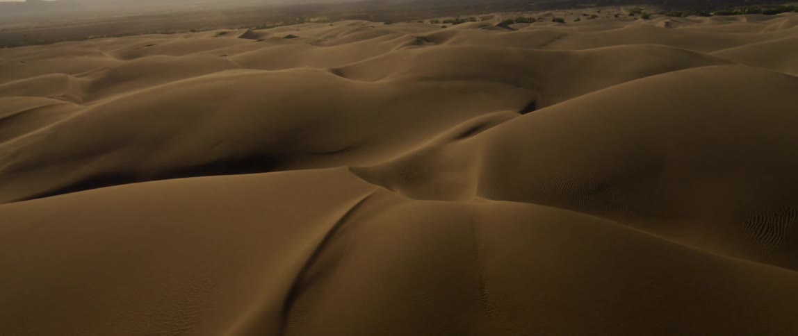 Sun sets over sandy hilly desert