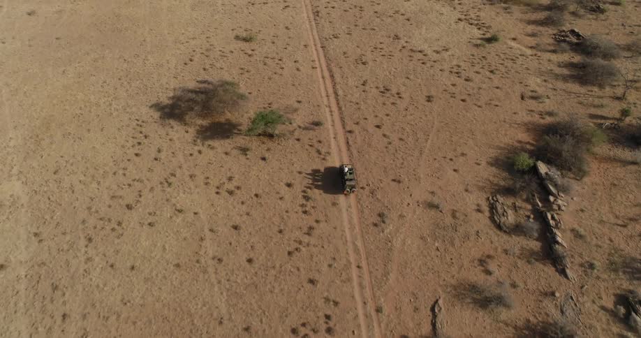 Vehicle drives on a dirt path through the desert