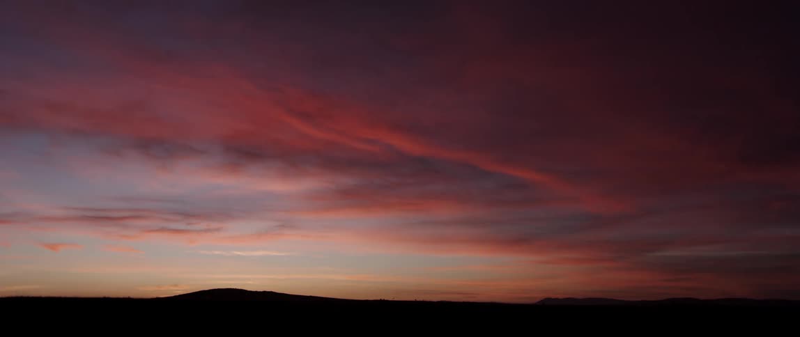 Sun sets over a hill and flat land