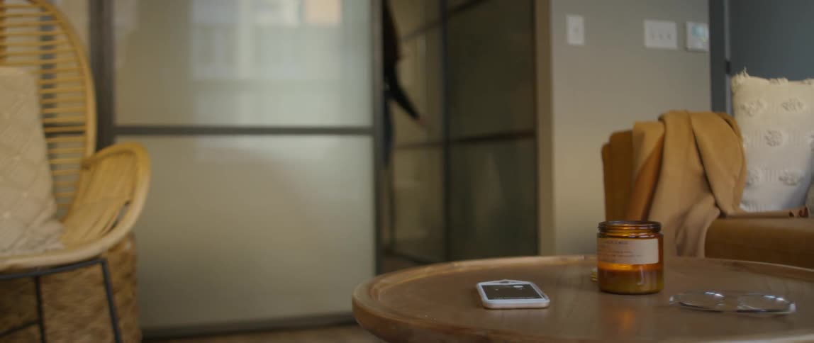 Woman enters room and lifts phone off coffee table