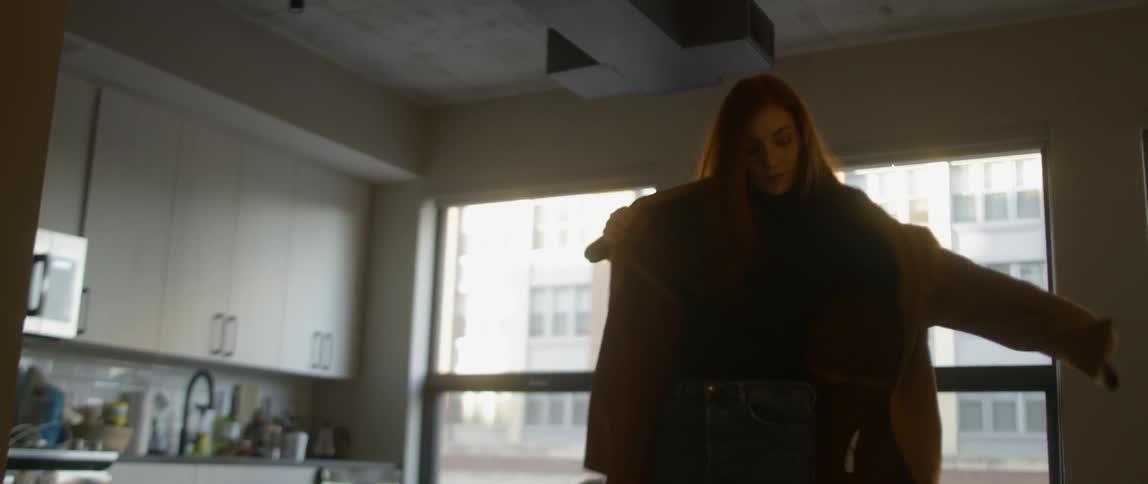 Woman sitting on a couch puts on her shoes and stand up to put a sweater on and leaves