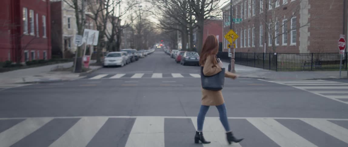 A woman looks back as she crosses a city street