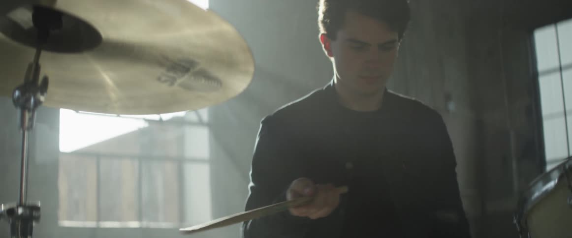 Drummer sits behind his kit and twirls one drumstick