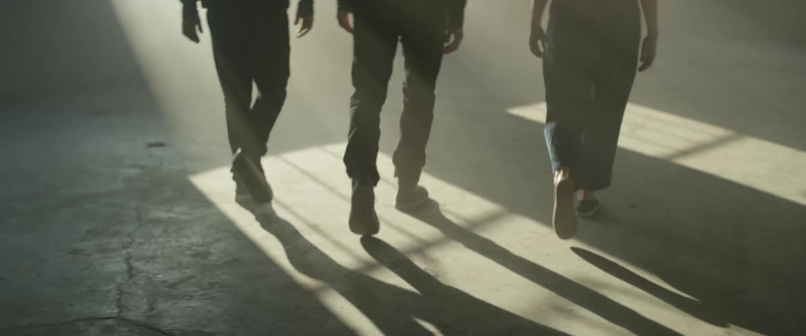Three people walk in a room on a sunny day