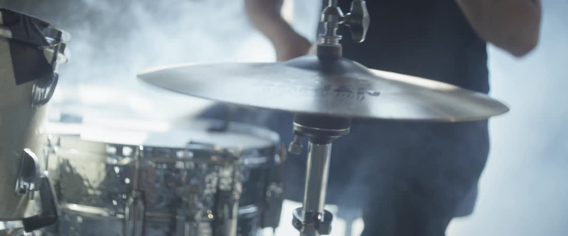 A drummer plays the drums with fog swirling around the drums