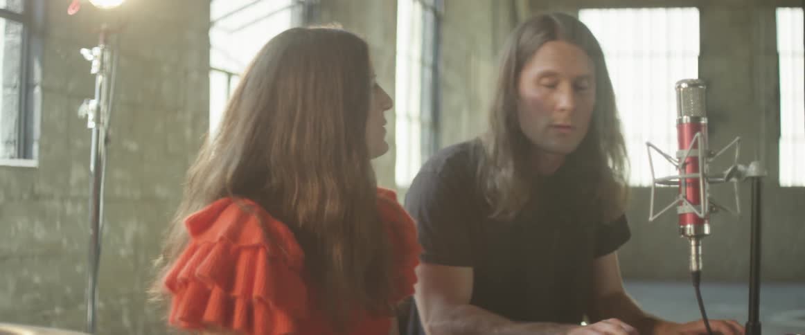 Woman and man talk in a lit up studio