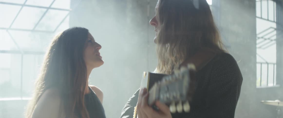 A man plays guitar as he sings with a woman