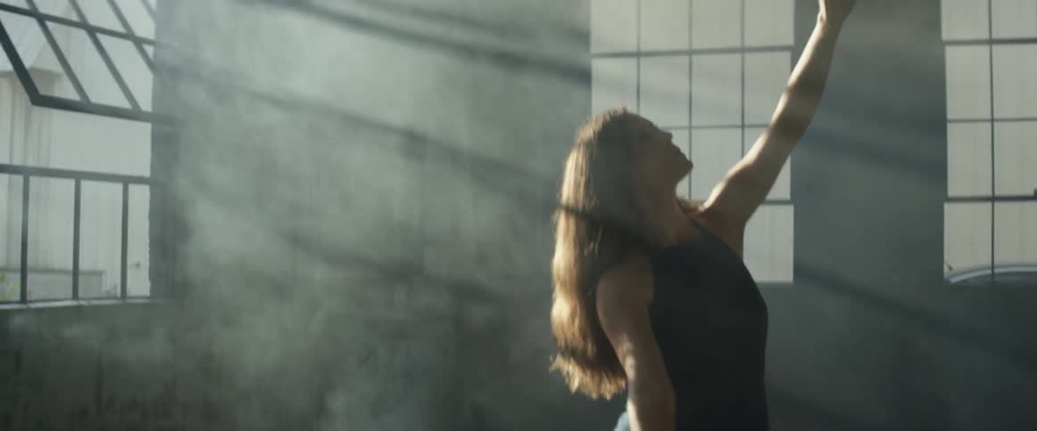A woman dances in the sunlight coming through the windows