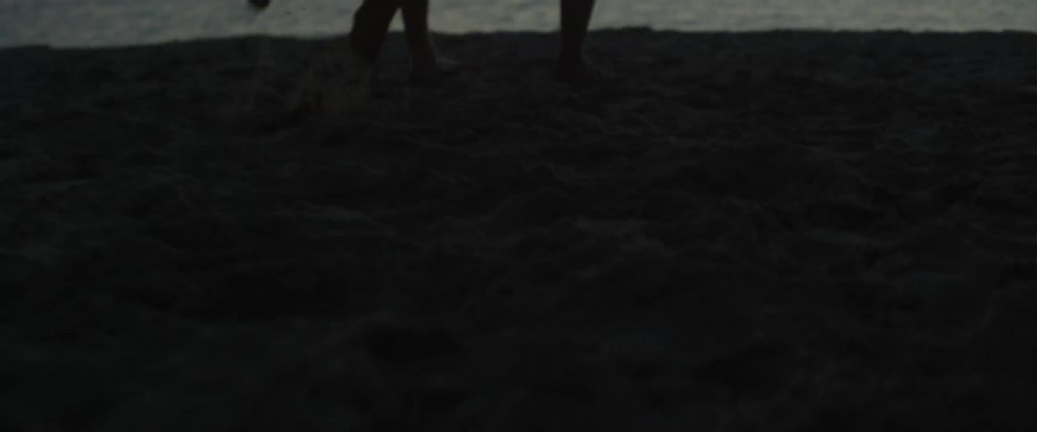 Two people run on the beach at sunset
