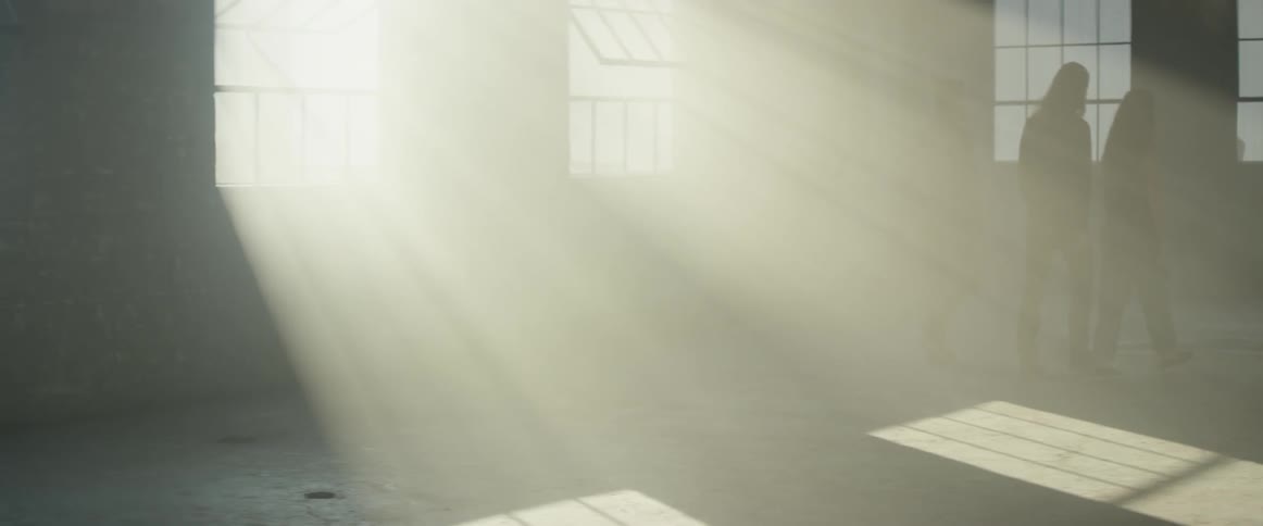 Sunshine streams through open windows as men walk past