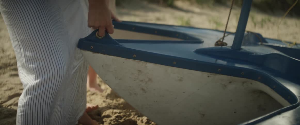 A man pulls a boat on the sand