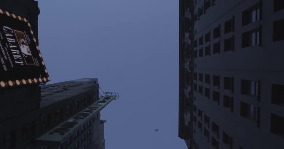 A view straight up of flying between tall buildings at twilight
