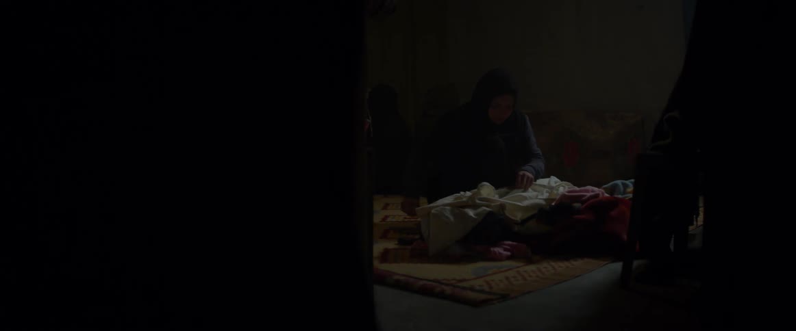 A woman sits on the floor and tears cloth into strips