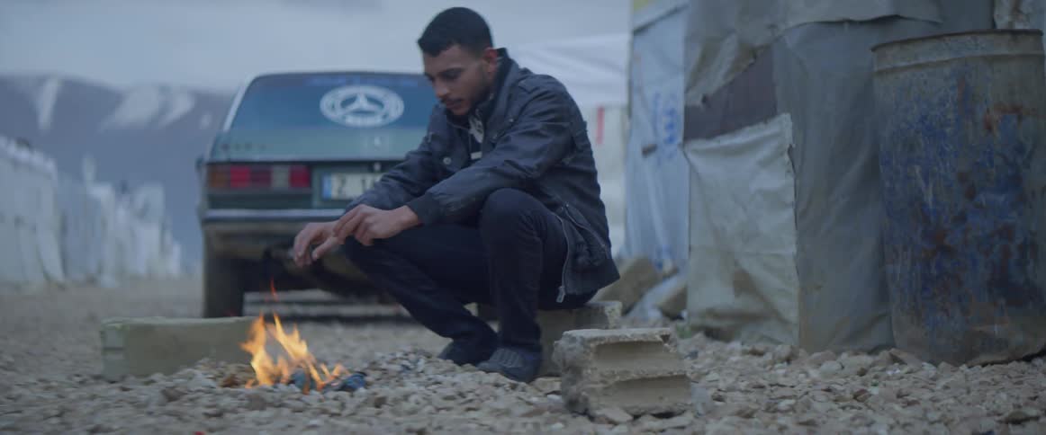 A man warms his hands by a fire