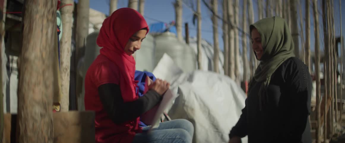 Person hands a woman a blanket and she gets up to walk away