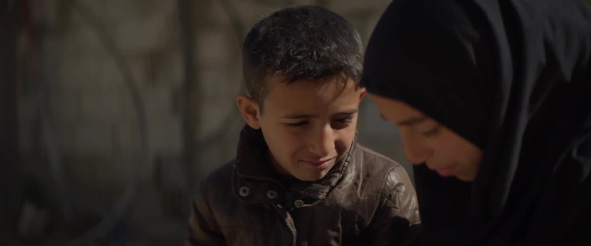 A boy nods and smiles as his sister talks to him