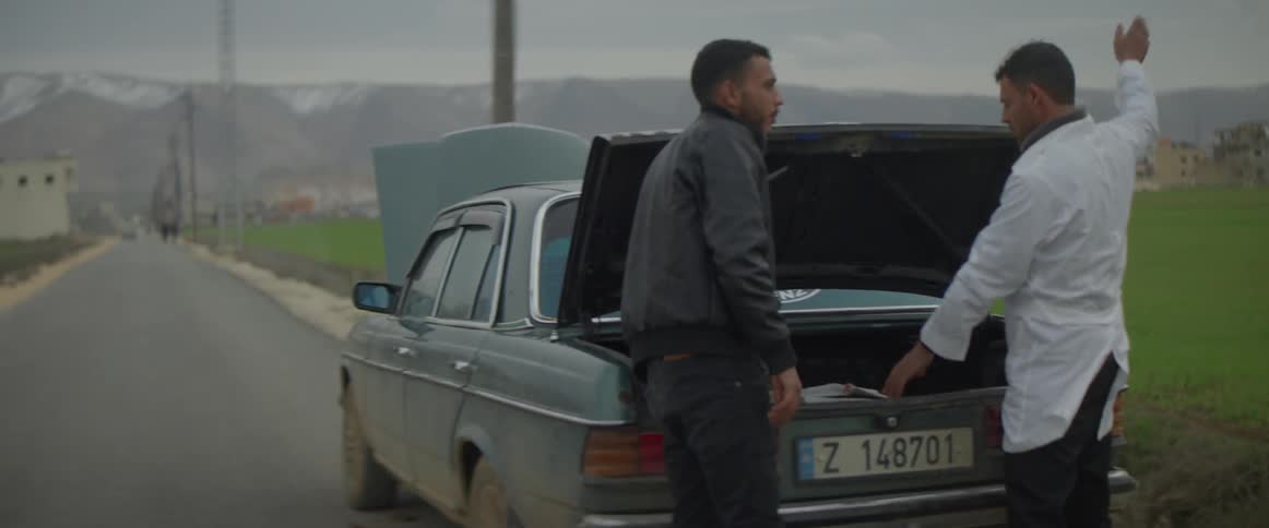 A man carries a box over to the vehicle