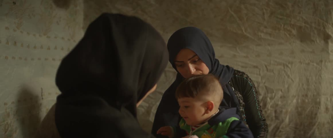 Two women sit and talk and play with a child
