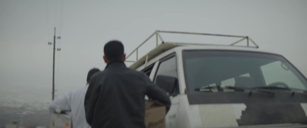 Man looks under a hood and walks around the vehicle and gets in