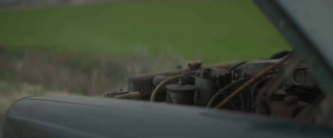 Car parked on the side of a country road with a smoking engine