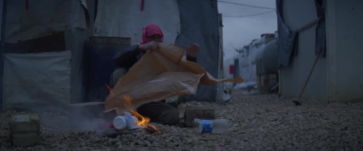 Woman builds a fire using trash