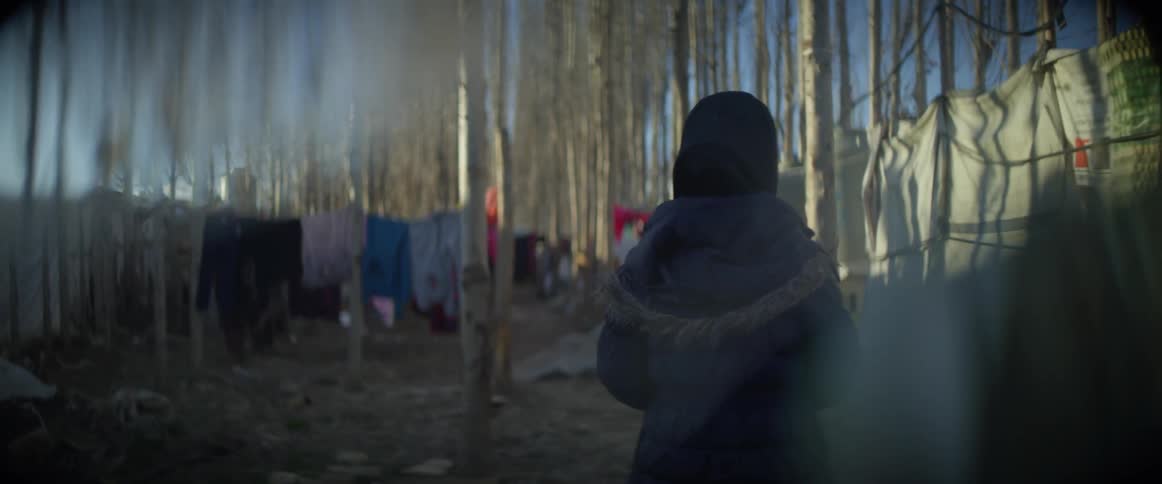 The person walks past the back of the tents
