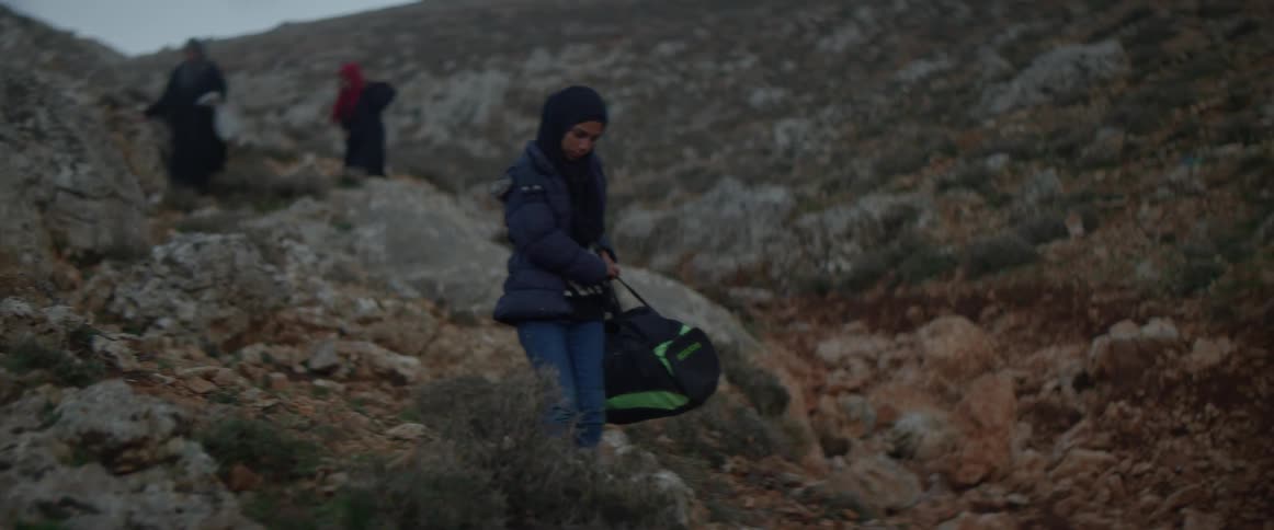 Refugees are crossing a rugged landscape at dusk