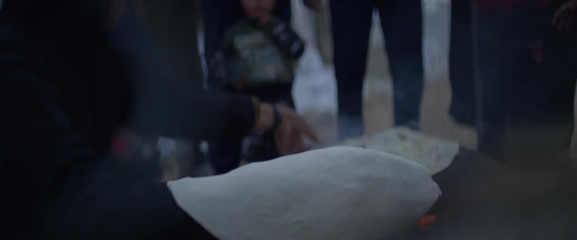 A person is cooking flatbread on a flame