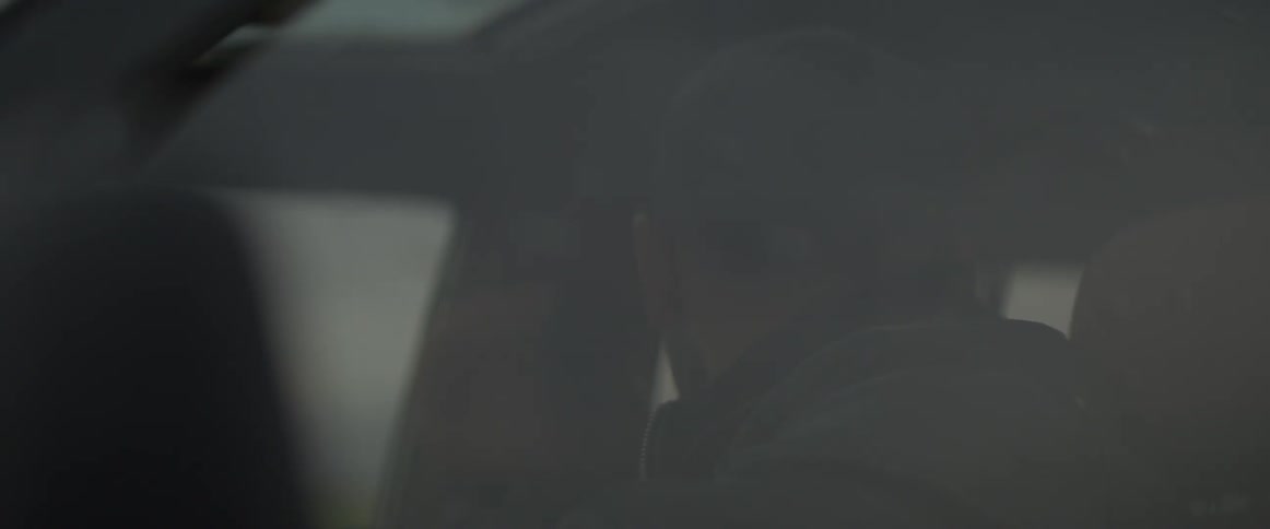 A man is looking behind himself as he drives in daylight