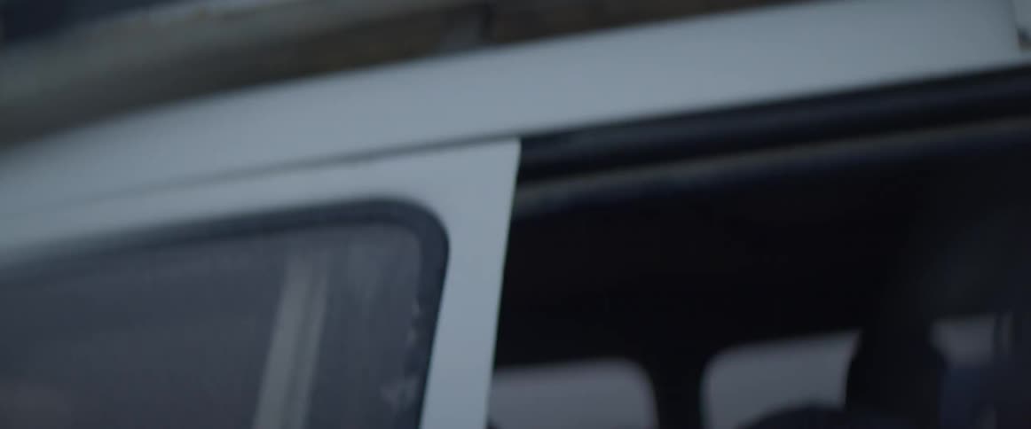 Several people run and shove each other to get into a white vehicle
