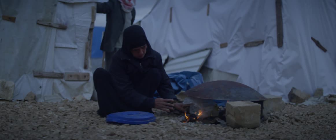 A person is working near a campfire at sunset