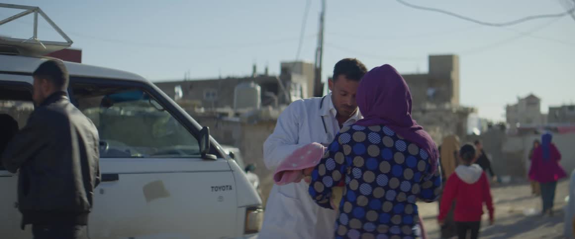 Doctor gets out of a vehicle and examines a woman's baby